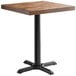 A Lancaster Table & Seating square wooden table with a black cast iron base.