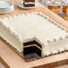 A black Enjay laminated corrugated sheet cake pad under a cake with two slices cut out.