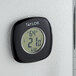 A Taylor digital thermometer and hygrometer on a white wall.