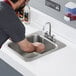 A man washing his hands in a Regency drop-in sink.
