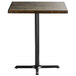 A Lancaster Table & Seating square wood table with a black cast iron base.