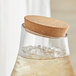 A glass jar with a cork lid filled with clear liquid and ice.