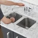 A person filling a glass with water from a stainless steel Waterloo undermount sink.