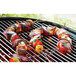 Outset stainless steel skewers holding vegetables and meat cooking on a grill.