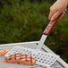 An Outset stainless steel fish turner being used to cook salmon on a grill.