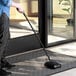 A person using a Choice 9" Single Brush Floor Sweeper to clean the floor.