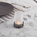 A Sterno black metal three ring candle holder on a table with a white candle.