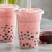 Two plastic cups of pink Bossen dragon fruit smoothie with black balls and straws.