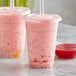 Two plastic cups with pink Bossen Strawberry Concentrated Syrup smoothies and straws.