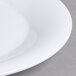 A close up of a Carlisle white melamine plate with a wide white rim.