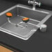 A Guardian Equipment AutoFlow left hand deck mounted eye and face wash station with two orange faucets above a metal sink.