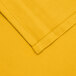 A gold fabric square with a folded and hemmed edge.
