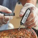 A person in gloves using an AvaTemp digital pocket probe thermometer to check the temperature of meat.