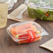A close-up of a Choice clear plastic deli container filled with salad on a table with a white plastic spatula.