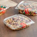 Two Choice clear plastic deli containers with nuts and candy on a table.