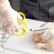 A person using yellow-handled Mercer Culinary poultry shears to cut a chicken.