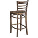 A Lancaster Table & Seating wooden bar stool with a ladder backrest and a wooden seat.