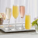 A tray with three Libbey Embassy flute glasses of champagne with yellow flowers.