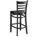 A Lancaster Table & Seating black wood ladder back bar stool with a black wood seat and backrest.