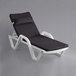 A white Lancaster Table & Seating chaise lounge chair with black cushion and pillow.