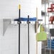 A Regency mop and broom holder shelf with cleaning tools and mops on it.