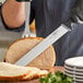 A person using a Schraf slicing knife to cut a piece of meat.