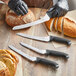 A hand in a glove using a Schraf serrated bread knife to cut a loaf of bread.