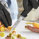 A gloved hand uses a Schraf serrated paring knife to cut a carrot.