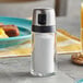 An OXO Good Grips salt shaker on a table next to food.