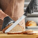A person using a Schraf serrated knife to slice bread.