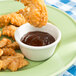 A plate of chicken strips and french fries with a bowl of Thunder Group Bone Smooth Melamine Ramekin on the table.