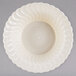 A Fineline Flairware ivory plastic bowl with a wavy design on the edge.