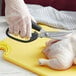 A person using Tablecraft stainless steel poultry shears to cut a chicken.