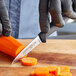 A person using a Dexter-Russell 36000 paring knife with a black handle to peel a carrot.