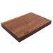 A John Boos & Co. black walnut wood cutting board with rustic edges on a table.