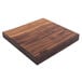 A square John Boos black walnut wood cutting board on a table with rustic edges.