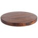 A round John Boos black walnut wood cutting board on a table.