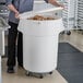 A person using a 55 gallon white mobile ingredient storage bin to hold potatoes.