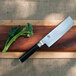 A Shun Classic Nakiri knife on a cutting board with broccoli.