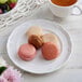 A white Acopa porcelain plate with a pink macaron on it.