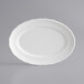 A white Acopa porcelain platter with a scalloped edge.