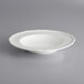 A white Acopa porcelain pasta bowl with a scalloped rim.