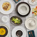 A table with Acopa Armor Gray scalloped wide rim bowls and plates of food on it.