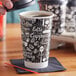A person pouring coffee into a black and white Choice paper hot cup.