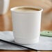 A white Choice double wall paper hot cup with a black straw on a counter.