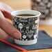 A hand holding a Choice Coffee Break double wall paper hot cup filled with coffee.