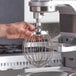 A person using an Estella wire whisk attachment on a mixer.