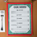 An 8 1/2" x 11" green menu with angled marble border on a table.