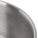 A close up of a silver stainless steel bowl with a handle.