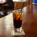 A glass of ice tea with a black Aardvark paper straw on a table.